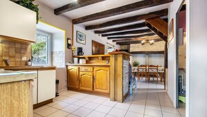 A kitchen with wooden cabinets, a tiled floor, and a dining area with a table and chairs.