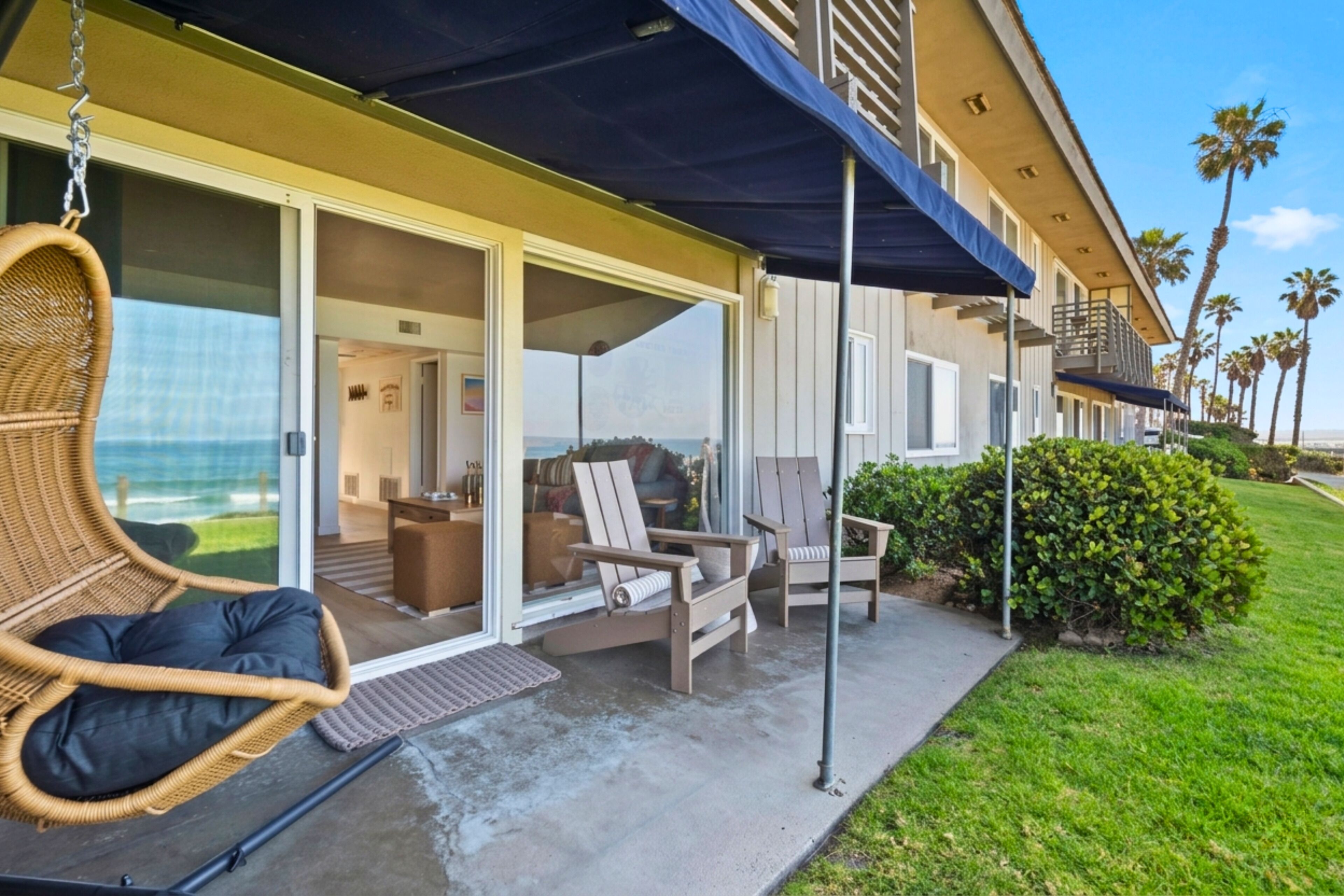 A hotel with a covered outdoor seating area, a swing chair, and a view of the ocean.