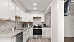 A modern kitchen with white cabinets, stainless steel appliances, and a granite countertop. - Columbus Villa 107 - 3 bedroom on the boardwalk with great beach and ocean views~ (Ocean City)