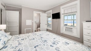 A bedroom with a bed, a dresser, a TV, and a window with a beach view. - Columbus Villa 107 - 3 bedroom on the boardwalk with great beach and ocean views~ (Ocean City)