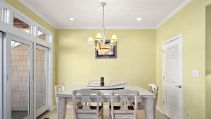 A dining area with a table, chairs, a chandelier, and a door with a window. - Pelican Perch - 3 bed/ den on water with boat dock and outdoor pool - 36th St area sleeps 10 (Ocean City)