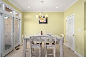 A dining area with a table, chairs, a chandelier, and a door with a window. - Pelican Perch - 3 bed/ den on water with boat dock and outdoor pool - 36th St area sleeps 10 (Ocean City)
