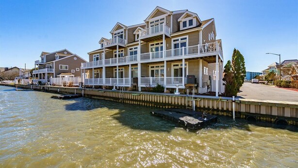 A waterfront property with multiple balconies, a dock, and a clear view of the water. - Pelican Perch - 3 bed/ den on water with boat dock and outdoor pool - 36th St area sleeps 10 (Ocean City)