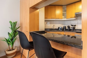 Une cuisine moderne avec des meubles en bois, un plan de travail noir et une plante en pot.