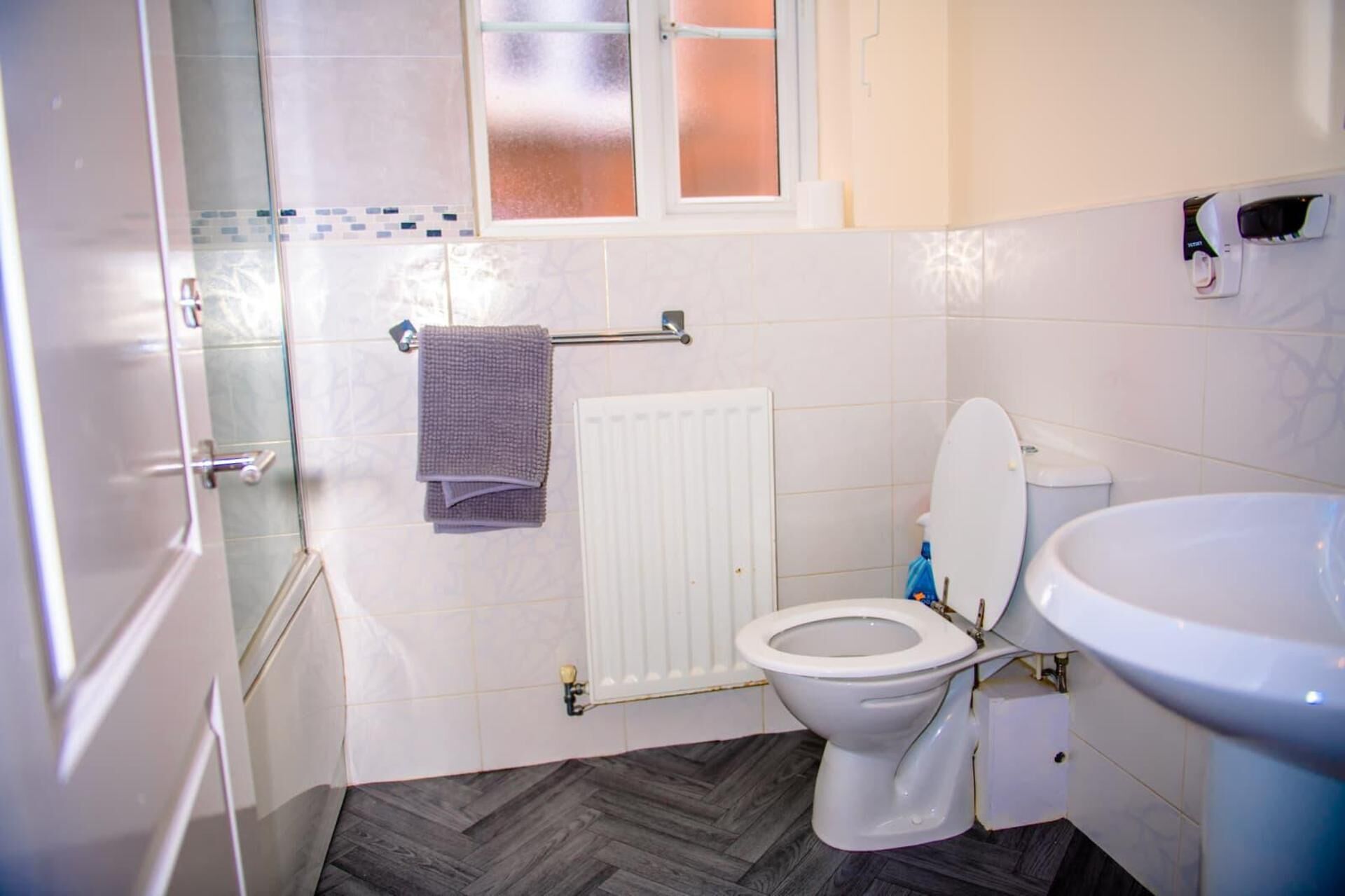 Une salle de bain comprenant des toilettes, un lavabo, un porte-serviettes et un espace douche.