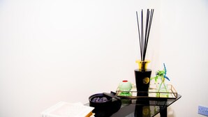 Uma mesa de vidro preto com um livro, uma tigela de carvão e um vaso preto com detalhes amarelos.
