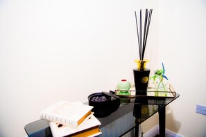 Ein schwarzer Glastisch mit einem Buch, einer Schale Holzkohle und einer schwarzen Vase mit gelber Oberseite.