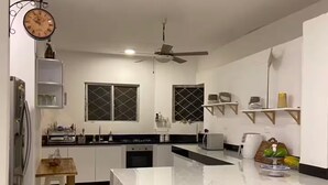 Une cuisine moderne dotée d’un îlot central, de meubles blancs et d’un ventilateur de plafond.