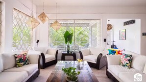 Un salon moderne avec une table basse en bois, des canapés blancs et une grande fenêtre donnant sur un paysage verdoyant.