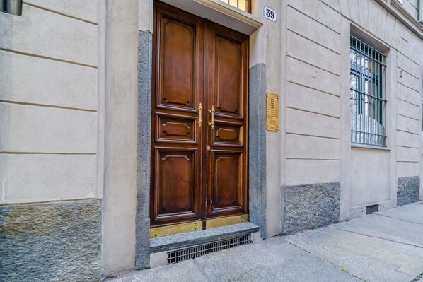 Ein Gebäude mit einer großen Holztür, einem kleinen Fenster mit Gitterstäben und der Hausnummer 39 an der Wand.