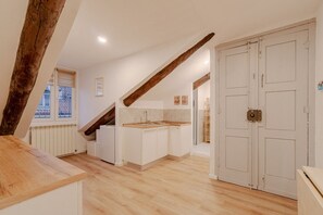 Eine moderne Küche mit Holzbalken, weißen Schränken und Blick ins Freie.