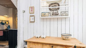 A wooden table with a chair, a shelf with decorative plates, and a trash can. - 6 Person Holiday Home in Stege (Stege)
