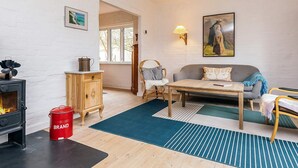 A cozy living room with a fireplace, wooden furniture, a sofa, and a painting on the wall. - 6 Person Holiday Home in Stege (Stege)