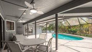 Eine Außenpatio mit Pool, überdachter Sitzgelegenheit und Deckenventilator.