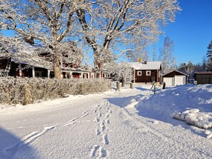 Un paisaje rural cubierto de nieve, con casas, cielo despejado y un sendero visible.