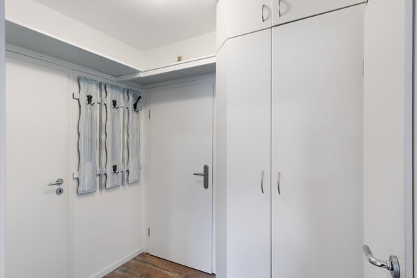Una habitación con un armario blanco, una puerta con manija y un perchero en la pared.