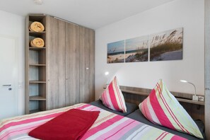 Ein Schlafzimmer mit einem Bett, einem Kleiderschrank, einem Nachttisch und einer Wandlampe.