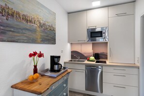 A modern kitchen with a built-in microwave, a coffee maker, and a sink. - Apartment "Dünenatelier" with Balcony and Wi-Fi (Norderney)