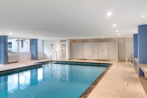 Une piscine dotée d’une terrasse carrelée, d’un espace vestiaire et offrant une vue sur l’extérieur.