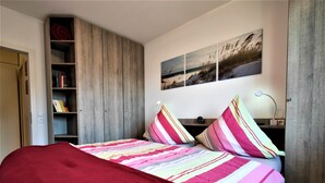 Ein Schlafzimmer mit einem Bett, einem Bücherregal und einem an der Wand befestigten Kunstwerk.