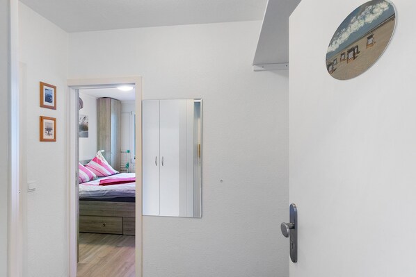 A bedroom with a bed, a wardrobe, and a door leading to another room. - Apartment "Dünenatelier" with Balcony and Wi-Fi (Norderney)