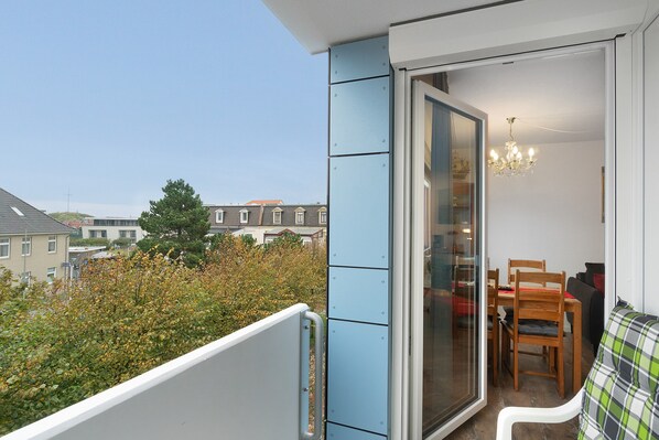 Ein Balkon mit Blick auf Wohnhäuser, eine Essecke mit Tisch und Stühlen sowie eine Kristallleuchter.