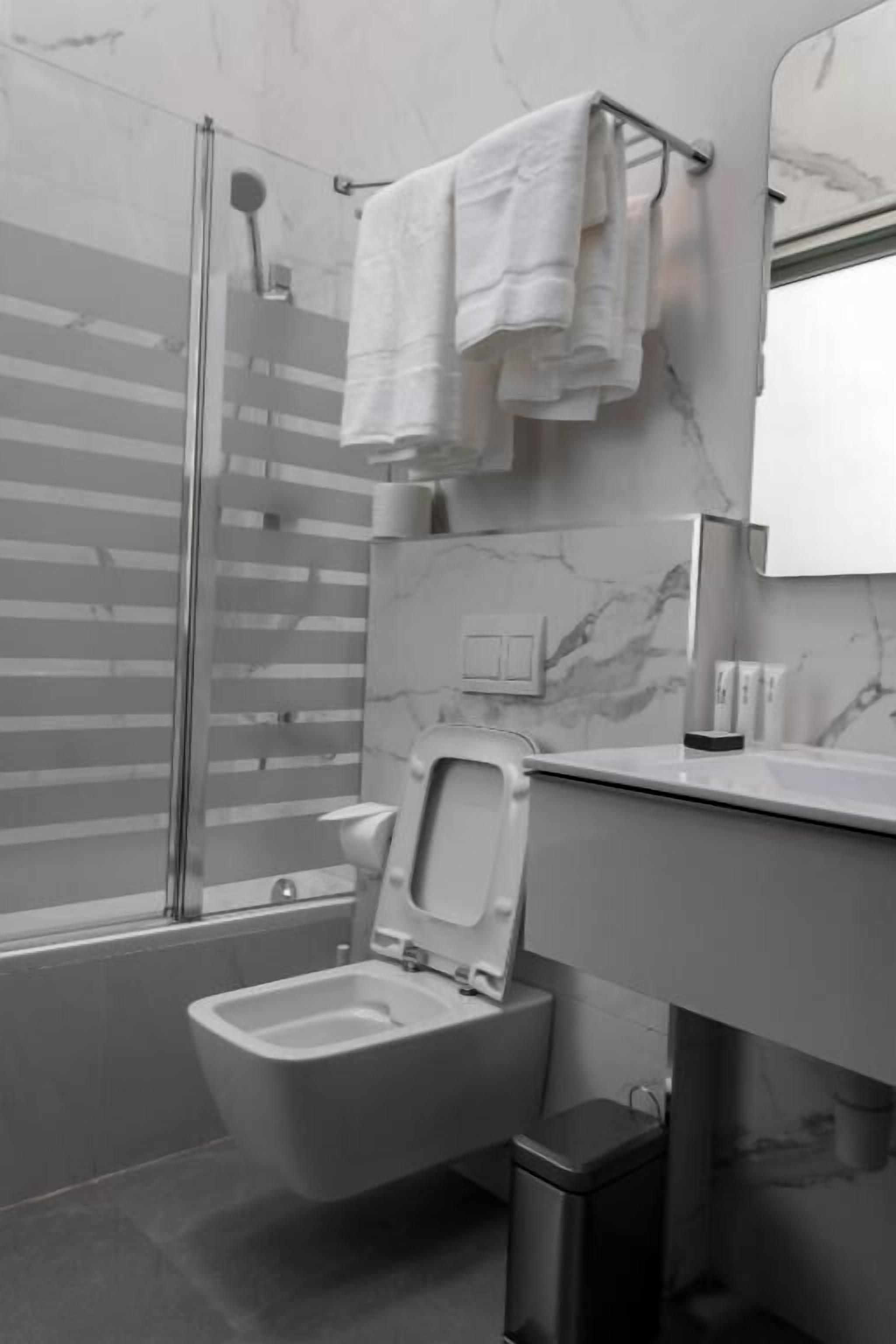 A modern bathroom with a shower, toilet, and sink.