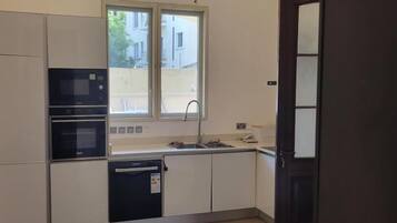 Une cuisine équipée d’appareils électroménagers intégrés, avec une fenêtre et une porte.
