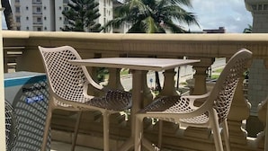 A balcony with a table and chairs, a trash bin, and a building in the background. - Clayhall By SRS (Lagos)