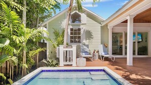 Un espace aménagé au bord de la piscine, comprenant une piscine, des chaises longues et une petite terrasse.