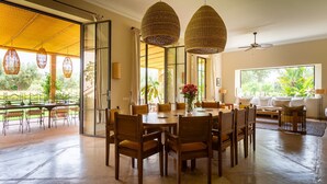 A spacious dining area with a large table and chairs, surrounded by large windows and a view of greenery. - Nyssa, swimming pool, pétanque, garden & staff (Marrakech)