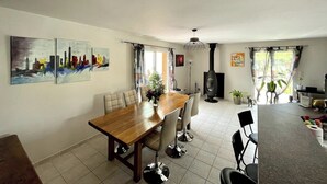 A dining area with a wooden table and chairs, a sofa, a fireplace, and artwork on the walls. - Detached house, fully fenced, swimming pool, bowling green, dogs welcome. (La Bezole)