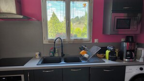 A kitchen with a sink, a microwave, a coffee maker, and a washing machine. - Detached house, fully fenced, swimming pool, bowling green, dogs welcome. (La Bezole)