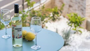 Een ronde tafel met een fles witte wijn, twee glazen en een citroen.