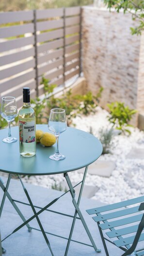 A round table with a bottle of white wine, two glasses, and a lemon.