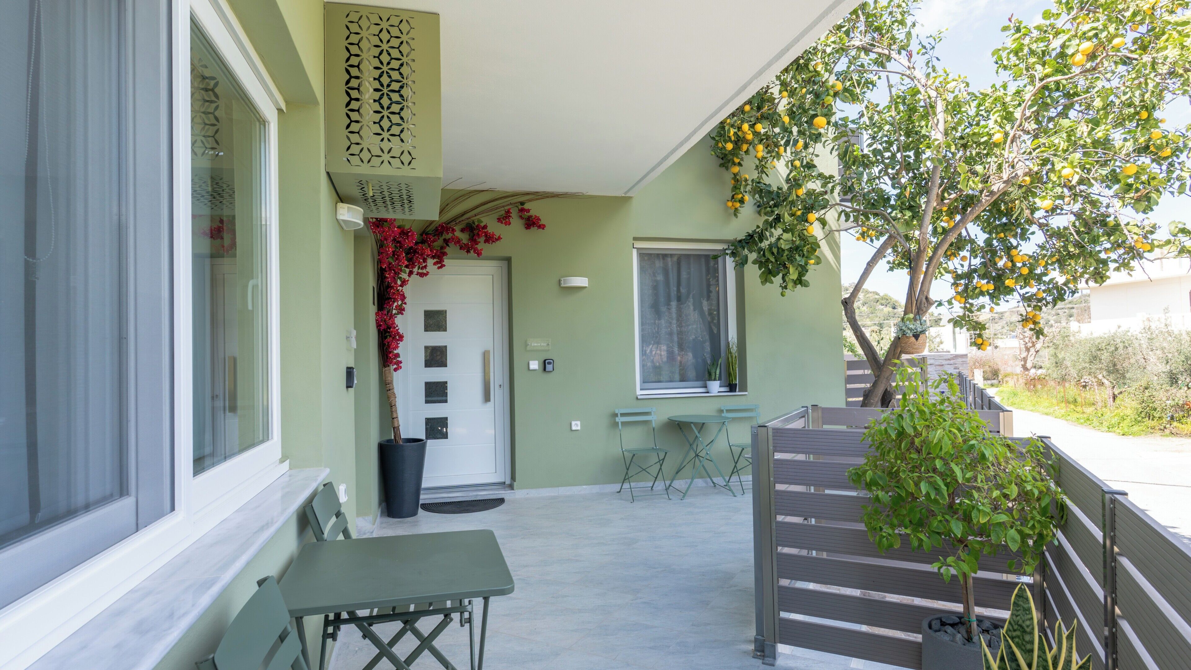 A covered outdoor area with a table and chairs, a potted plant, and a decorative wall panel.