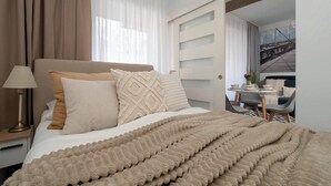 Een hotelkamer met een bed, een nachtkastje, een lamp en uitzicht op een trap en een eetgedeelte.
