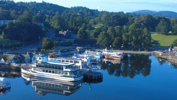 A riverfront marina with docked boats and a large white boat with a green roof. - Rigg & Rest - Central Bowness, Balcony & Parking (Bowness-on-Windermere)