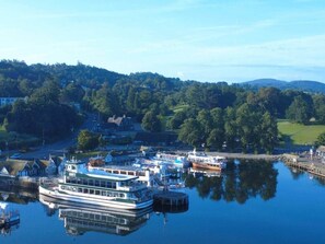 A riverfront marina with docked boats and a large white boat with a green roof. - Rigg & Rest - Central Bowness, Balcony & Parking (Bowness-on-Windermere)