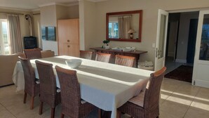 A dining area with a table set for six, surrounded by wicker chairs.