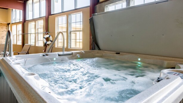 Un bain à remous avec un revêtement extérieur en pierre, un robinet et une bouée de sauvetage.