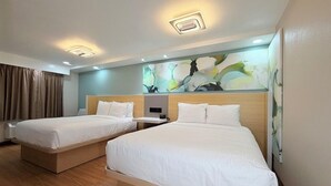 Une chambre d’hôtel avec deux lits, un luminaire au plafond, un tableau et une fenêtre avec des rideaux.