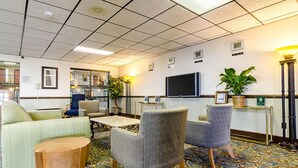 Un hall d’entrée avec des sièges, un comptoir de réception, un téléviseur et une horloge indiquant 10h37.