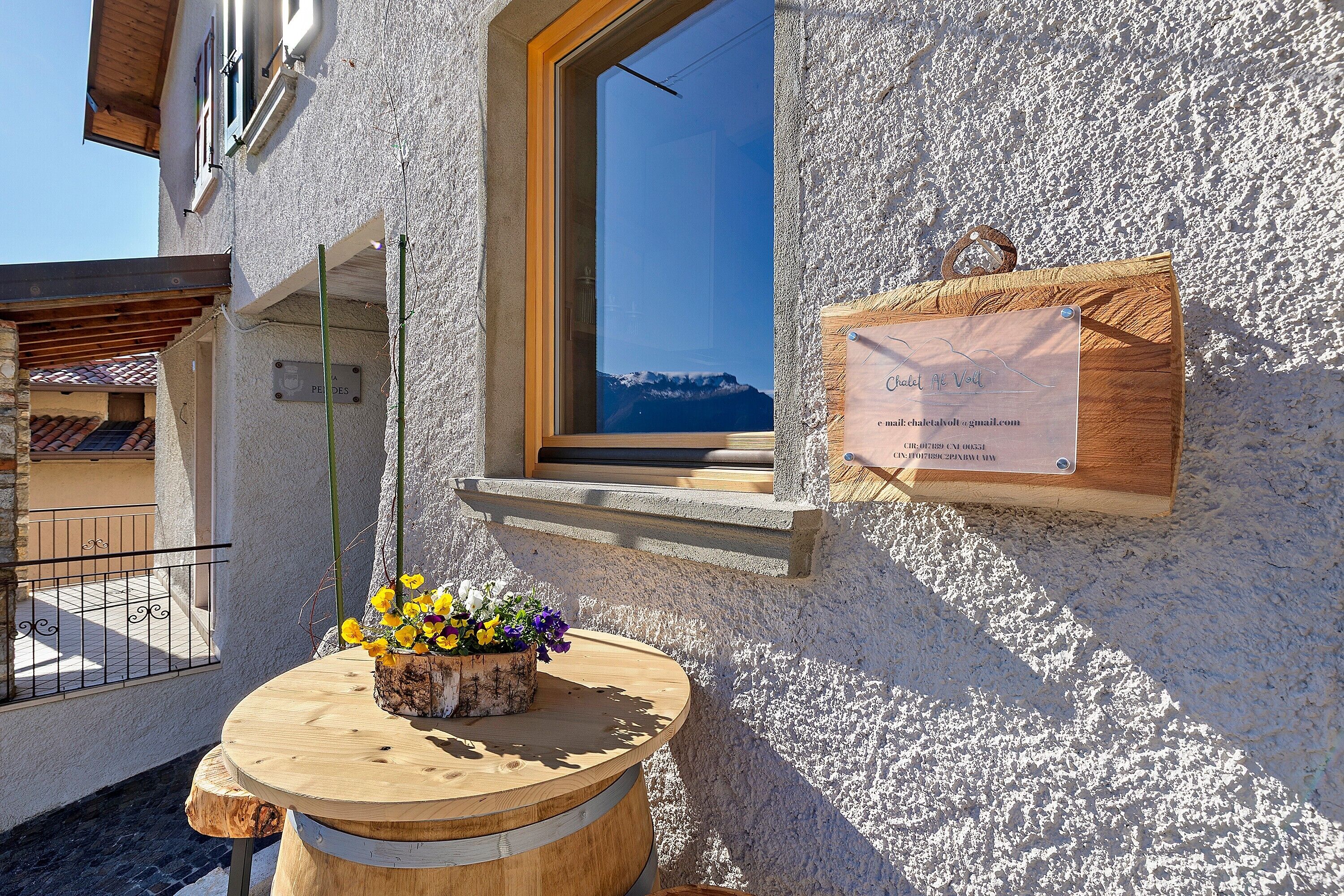 Un edificio con ventana que da a una montaña, una mesa de madera con flores y un letrero.