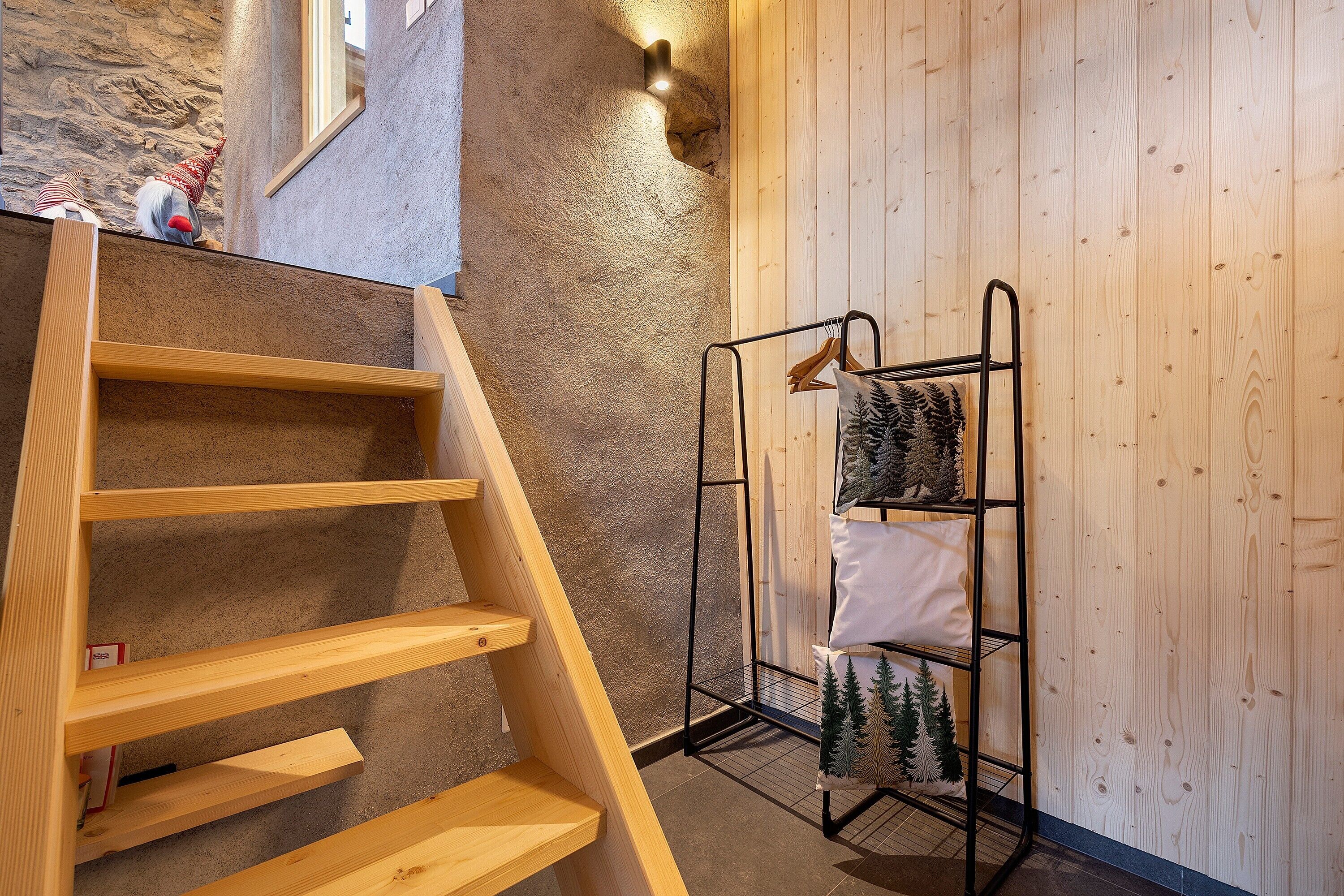 A wooden staircase, a metal rack with decorative items, and a textured wall.