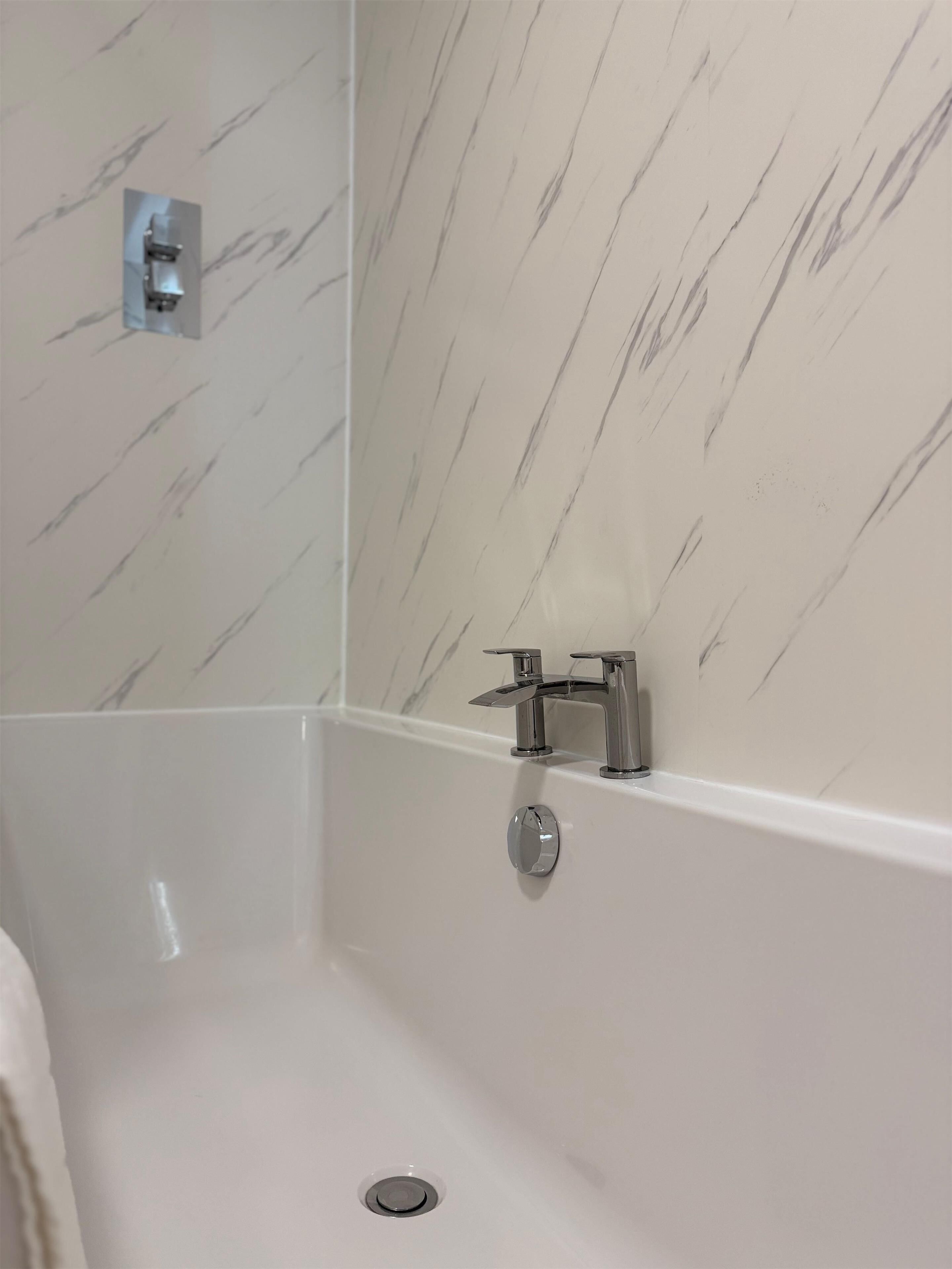 Un baño con ducha, grifo empotrado y desagüe.