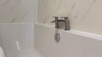 Un baño con ducha, grifo empotrado y desagüe.