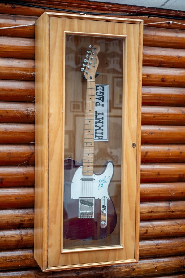 Une guitare électrique encadrée, portant une dédicace, est exposée sur un mur en bois.