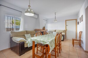 A dining area with a table, chairs, and a sofa. - Vacation Apartment in Chiclana with Pool and Garden (Chiclana de la Frontera)