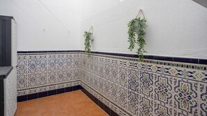 A corner of a room with patterned tile walls, a tiled floor, and hanging plants. - Vacation Apartment in Chiclana with Pool and Garden (Chiclana de la Frontera)